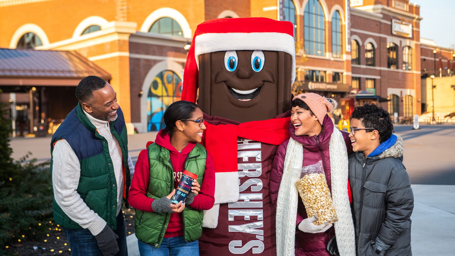 smiling family with hershey bar character dressed in holiday attire at hersheypark