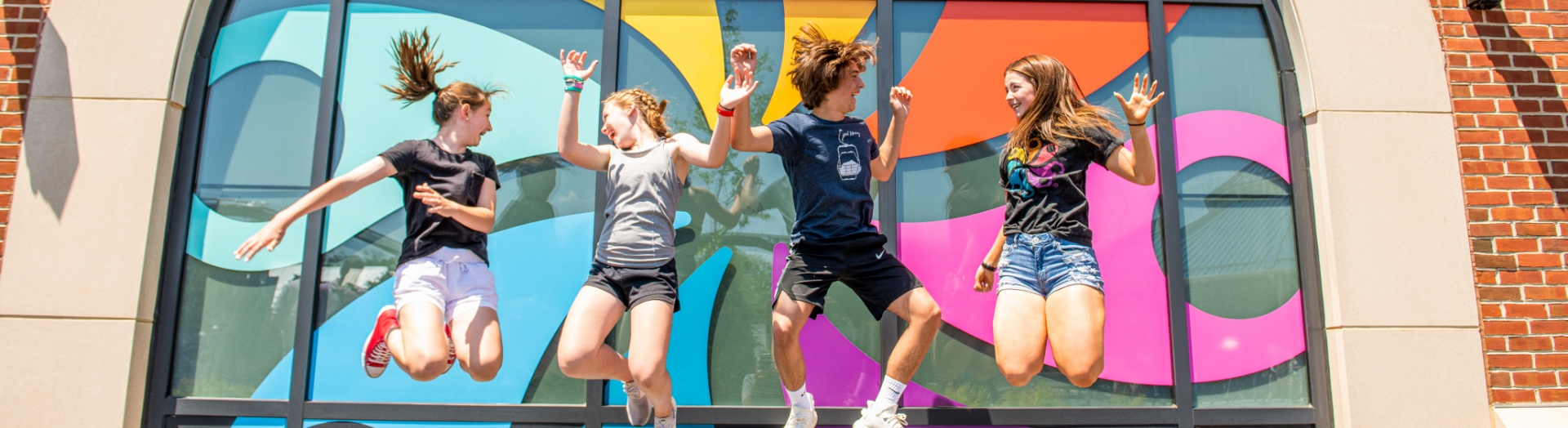 Teens jumping in front of pinwheel logo at Hersheypark