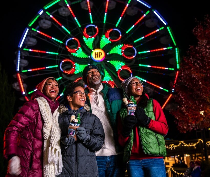 Family in front of ferris wheel lights at Hersheypark Christmas Candylane